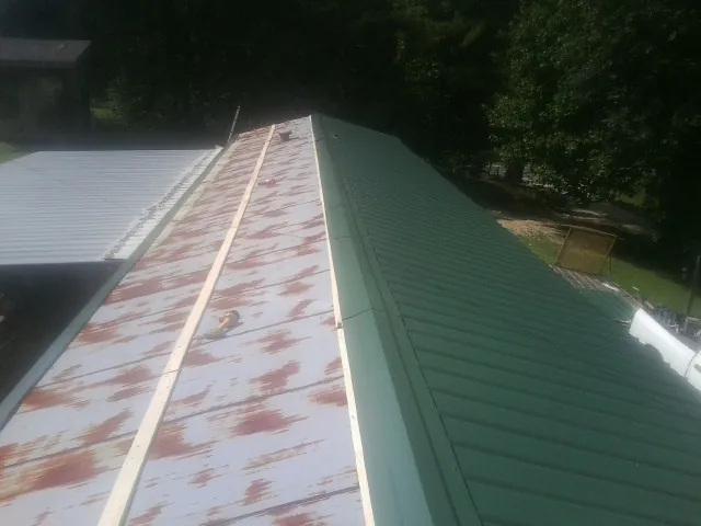 Old rusted panels beside newly installed green metal roofing — Wind Damage Roof Repair by Roofing Brothers in Oneonta