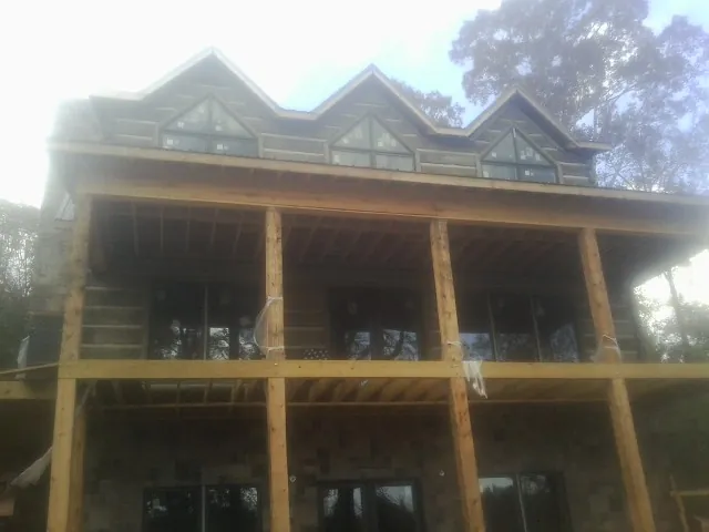 Dormers and porch framing on a large log home under construction — Roof Coating work by our crew in Oneonta